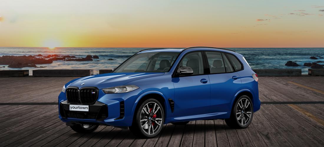 A blue BMW X5 M60i parked on a beachside pier at sunset.