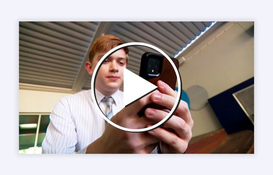 Teen using a phone with a play button in front.
