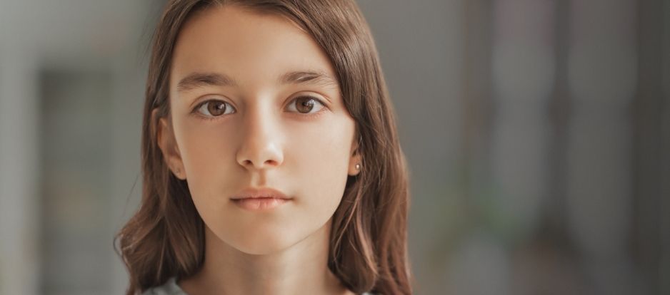 Tween girl looking to camera in darkened room