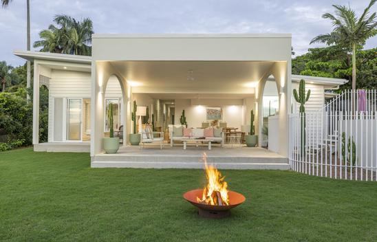 Lawn and firepit with 2 chairs and table looking into the Alfresco area.