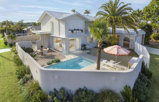 External view of a two storey house with a courtyard and swimming pool. 