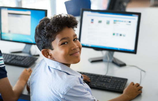 child looking a camera while browsing a computer